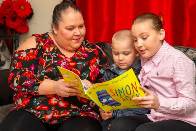 A mother and her two children reading a book.