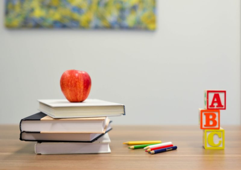 A photo of a school desk with books, pencils, and an apple on it