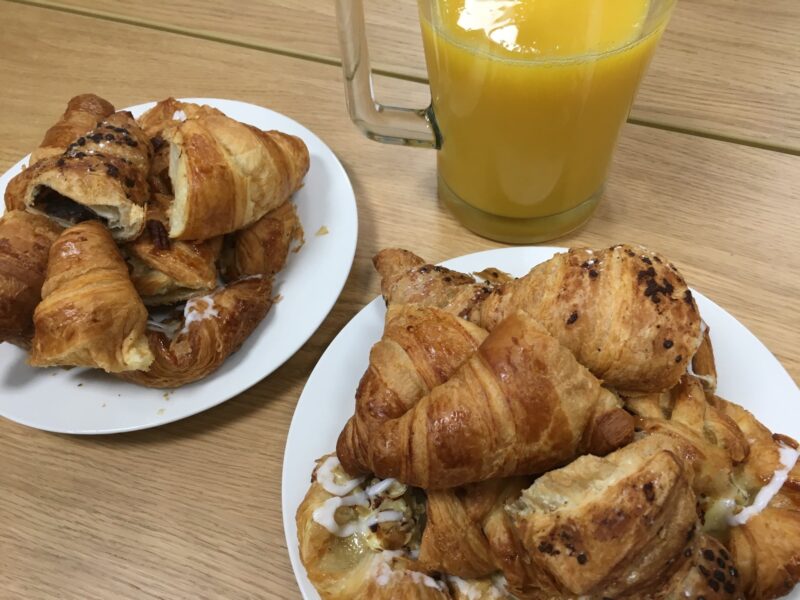 Pastries and two white plates with a glass of orange juice in the background