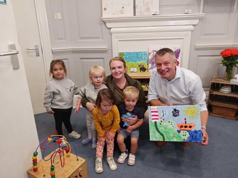 Luke Pollard picking up artwork made by children at the Bretonside Tops Nursery in Plymouth 